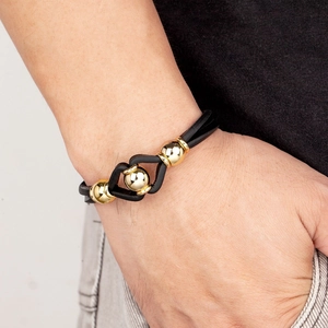 Bracelet pour homme en cuir tressé avec perle en métal doré porté au poignet