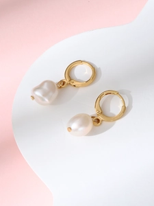 Macro shot of gold hoop earrings with white baroque pearl pendants on a wavy display