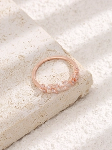 Détail d'une bague feuille or rose avec zircons sur un support de pierre blanc