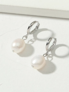 Close-up of elegant silver huggie hoop earrings with lustrous white oval pearls