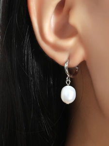 Close-up of elegant silver hoop earrings with a single white pearl on a model ear