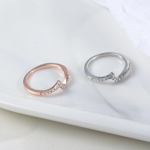 Elegant wave-shaped zircon rings in rose gold and silver displayed on marble