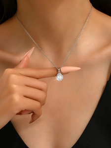 Gros plan d'un collier pendentif goutte en argent porté par un mannequin sur fond noir