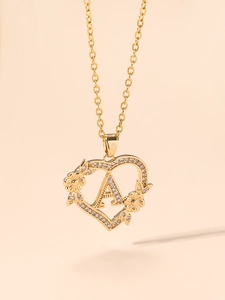 Dettaglio della collana con cuore dorato, lettera A, cristalli e accenti floreali