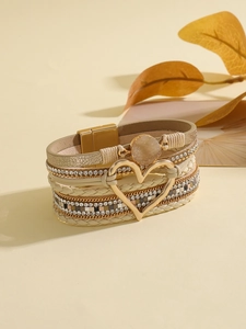 Detalle de una pulsera multicapa de cuero bohemio con corazón dorado y piedra natural