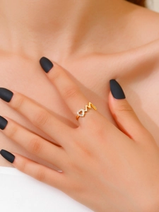 Detailed view of a gold M-letter ring with a sparkling pavé heart on a model's finger