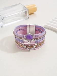 Detalle de pulsera boho multicapa con correas de cuero púrpura y cierre de corazón