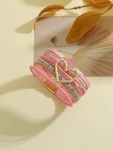 Detalle de la pulsera bohemia multicapa de cuero rosa con cierre magnético de corazón dorado