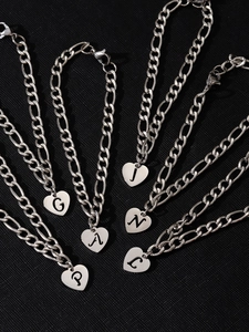 Dettaglio di ciondoli a cuore in argento con lettere incise su catene figaro in acciaio