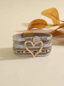 Detalle de la pulsera bohemia de cuero multicapa con cierre de corazón dorado y cristales