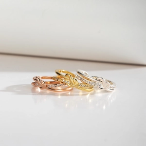 Macro detail of knot rings in gold, silver, and rose gold with pavé-set cubic zirconia
