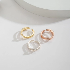 Three minimalist knot rings in gold, silver, and rose gold with pavé zircon accents