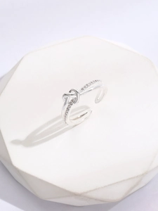 Detail of silver knot ring featuring white cubic zirconia stones on a white stand