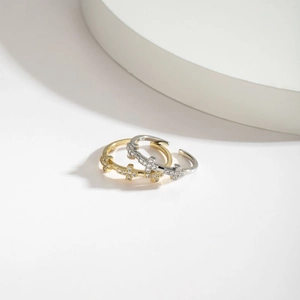 Detail of adjustable cross rings in gold and silver finish with pavé set zircon stones