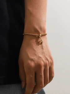 Dettaglio di un bracciale in acciaio al titanio dorato con ciondolo lettera A con strass lucidi