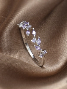 Macro shot of silver vine ring with purple zircon leaves on silk background