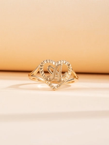 Dettaglio di un anello a cuore dorato con lettera A e trama radiale incisa