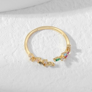 Adjustable gold ring with colorful zircon leaf cluster on a textured white stone background