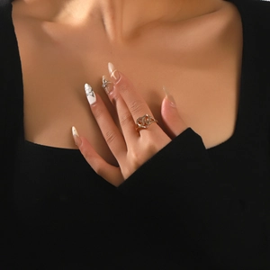 Dettaglio di un anello a cuore dorato con lettera intarsiata e cristalli sulla mano