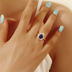 Detail of vintage gold ring with oval blue gemstone and white zircon cluster on finger