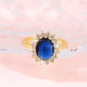 Elegant gold Diana ring featuring a large oval blue gemstone surrounded by white zircons