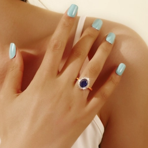 Classic blue sapphire style halo ring with rose gold band worn on a model's hand