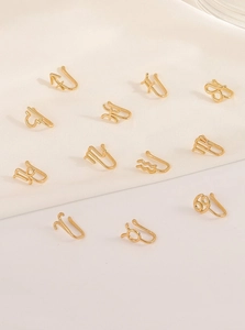 Detailed set of twelve gold-plated zodiac u-shaped non-piercing nose rings on satin fabric