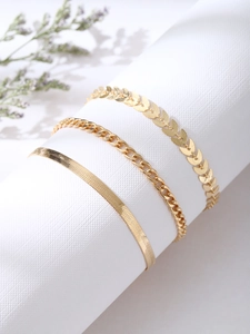 Détail d'un ensemble de trois bracelets de cheville dorés avec chaînes plates et épis