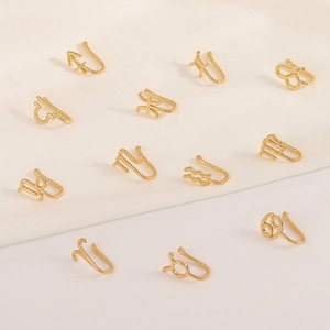 Golden non-pierced U-shaped 12 zodiac nose rings and ear clips set on silk fabric