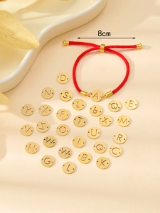 Détail du bracelet en cordon rouge tressé avec breloques lettres dorées interchangeables