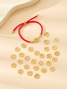 Détail de bracelets en corde rouge tressée avec breloques lettres dorées de A à Z