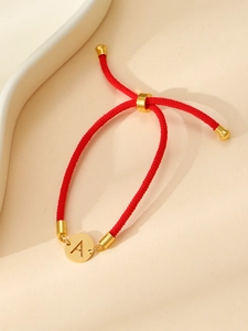 Détail d'un bracelet tissé rouge avec pendentif lettre A dorée réglable pour femme