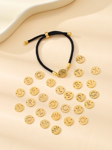 Détail d'un bracelet tissé noir avec pendentif lettre A dorée et breloques de A à Z