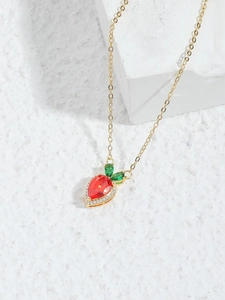 Detailed close-up of a luxury gold strawberry pendant with red gems and green leaves