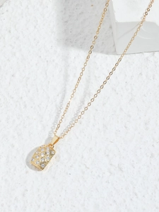 Close-up of golden quilted rectangular pendant with zircon accents on cross chain