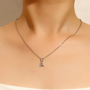 Detalle de collar de plata con colgante letra A y circonitas en cuello de modelo