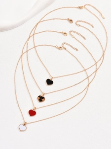 Detail showing four gold-plated heart necklaces in white, red, leopard, and black enamel