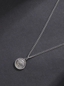Detailed shot of silver Evil Eye pendant with embossed eye motif and rope edge chain