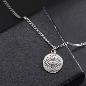 Minimalist evil eye pendant necklace with silver chain on black textured jewelry box