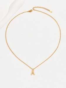 Close-up of golden necklace with bamboo texture letter A pendant and lobster clasp