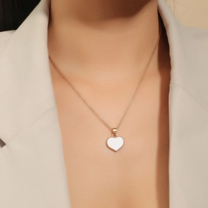 Elegant gold heart pendant necklace with white enamel inlay worn by a female model