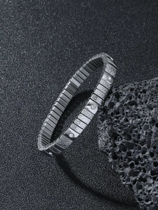 Macro detail of silver stainless steel stretch bracelet with diamonds on black volcanic rock