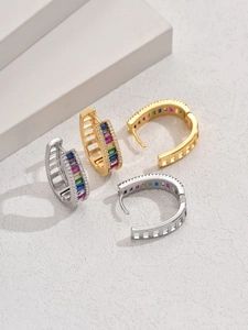 Détails de boucles d'oreilles créoles dorées et argentées avec zircons colorés et dentelle
