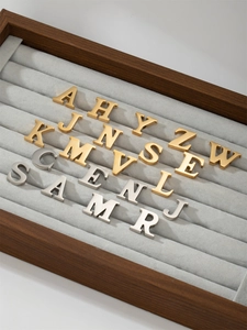 Macro view of 3D gold and silver letter charms with brushed metallic finish