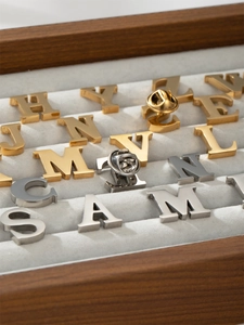 Macro detail of initial letter pins with gold and silver finish on velvet display