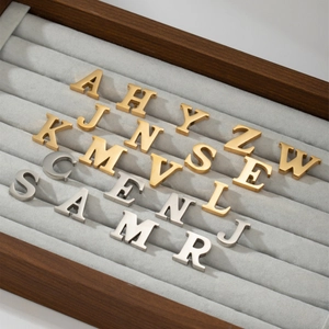Minimalist stainless steel 26 letter brooches in gold and silver finish on display