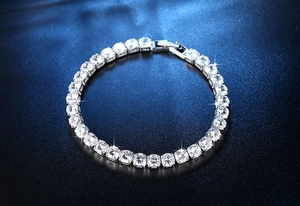 Makro-Detail eines silbernen Tennisarmbands mit runden Steinen und Klappverschluss