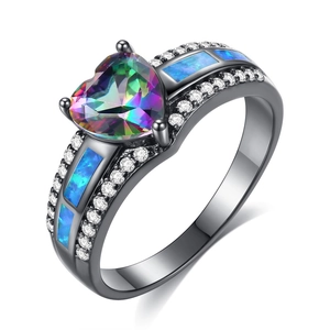 Detalle de anillo de oro negro con topacio místico de corazón y piedras de ópalo azul
