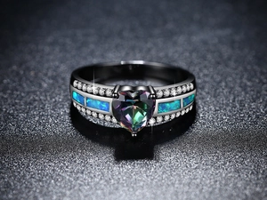 Detalle macro del anillo de topacio místico corazón con opale azul y banda negra