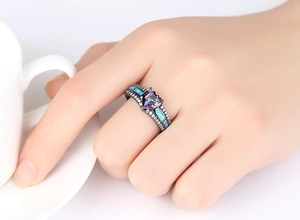 Vista macro de un anillo de opalo en forma de corazón con metal negro en la mano de una modelo